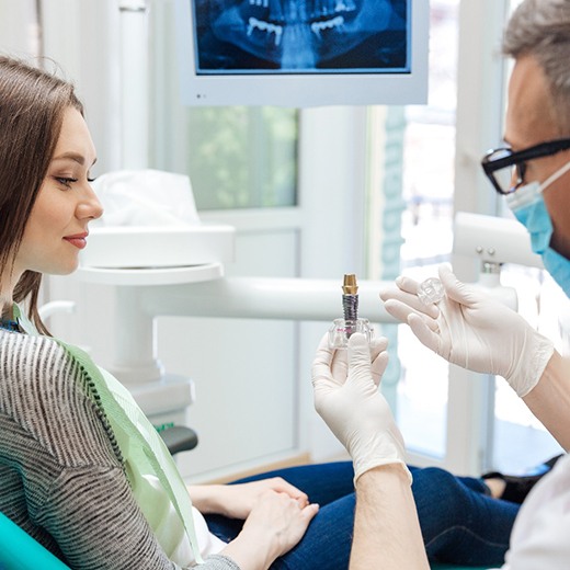 A dentist showing a dental implant to a patient