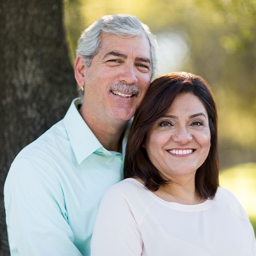 Man and woman smiling after receiving dentures