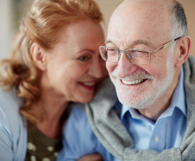 Older couple smiling after dental services