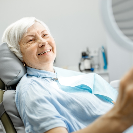 Smiling woman in dental chair after partial denture tooth replacement