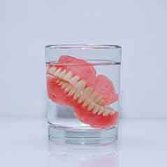 Removable dentures soak in glass of water