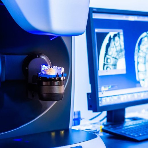 Printed dentures sitting on the machine bathed in blue light
