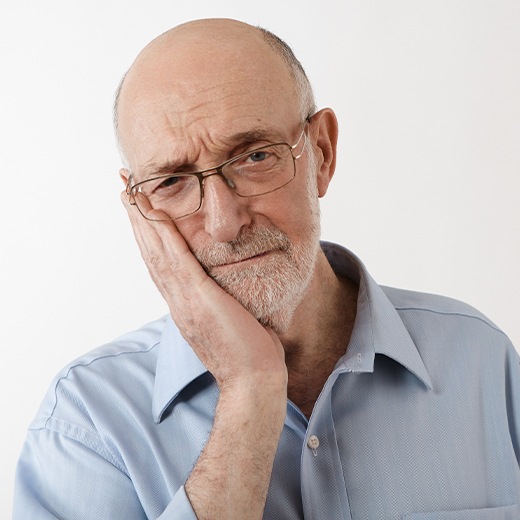 Patient holding cheek in pain before full mouth tooth extraction