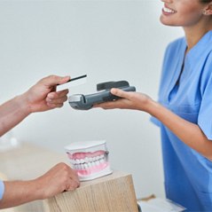 a patient paying for their tooth extraction in Cleveland, TX