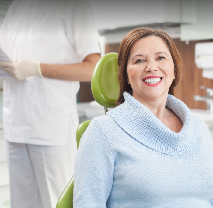 Woman smiling after receiving a new denture supported by dental implants