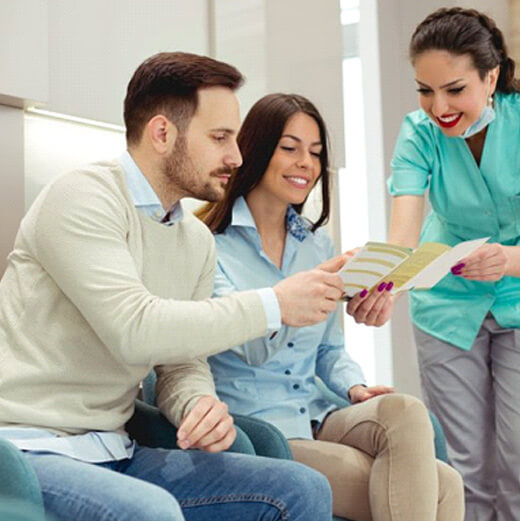 a dentist showing a couple a brochure on insurance