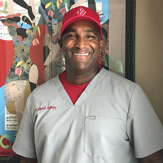 Doctor Guillory wearing scrubs and a red baseball cap
