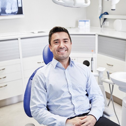 Male patient in button-up shirt smiling in chair