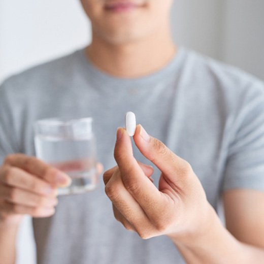 man holding pill and glass of water 