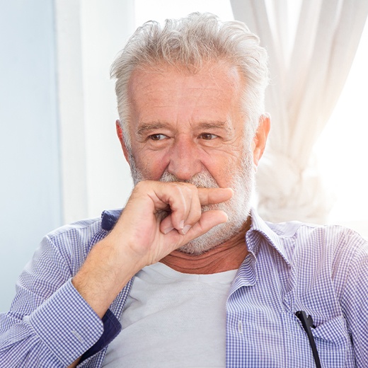 Older man with broken denture covering his mouth