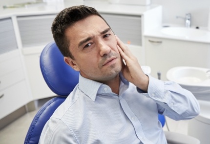 Man in pain in need of tooth extraction holding jaw