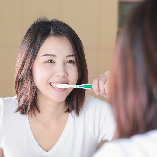 Woman smiling while brushing her teeth