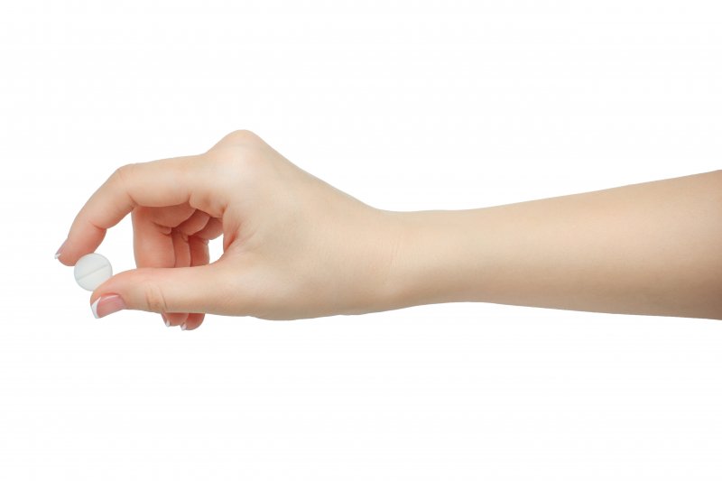 hand holding a small, round pill