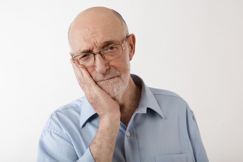 Man holding his cheek due to denture sores
